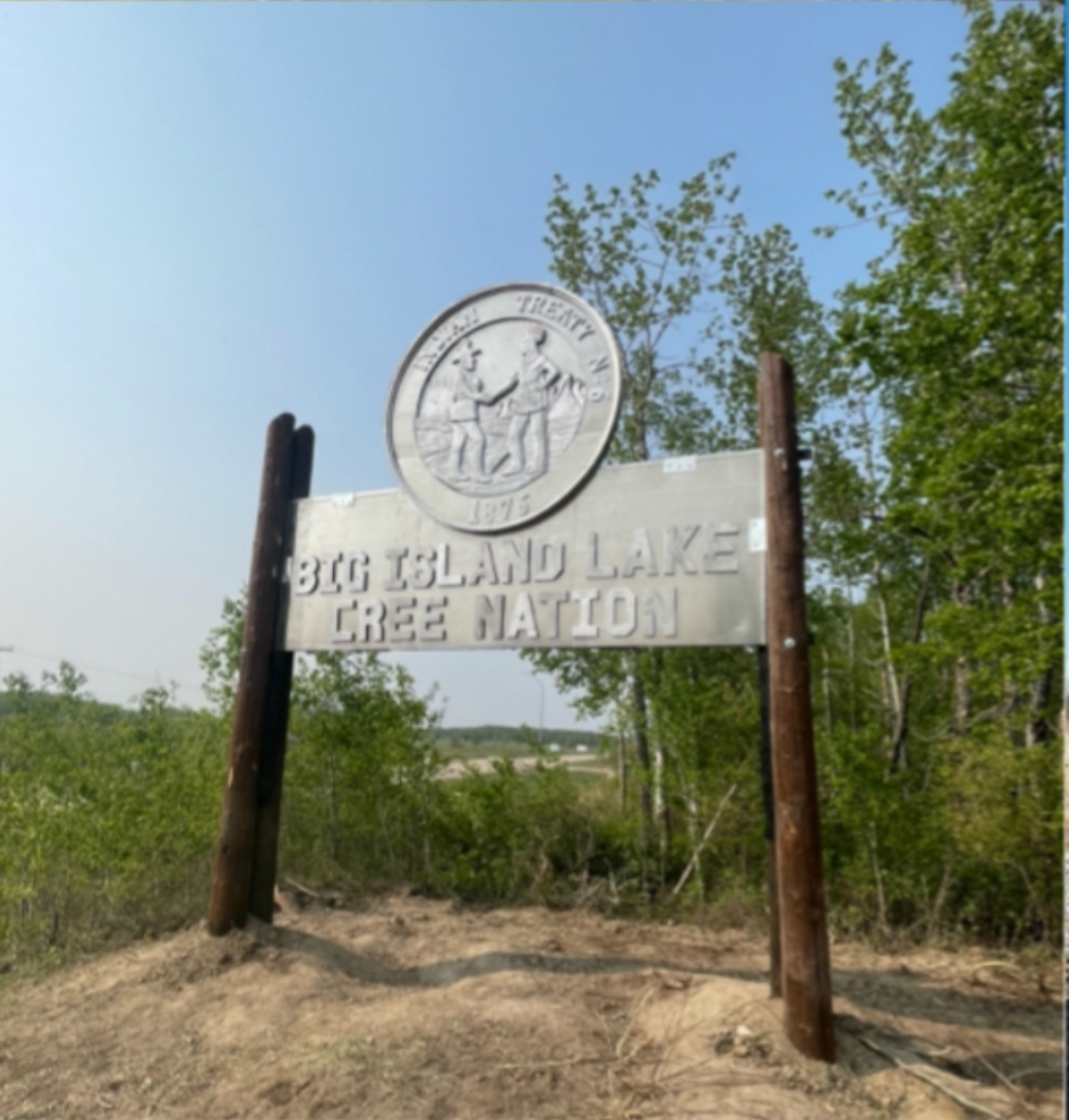Big Island Lake Cree Nation entrance sign with Treaty 6 medallion mounted on heavy timber posts