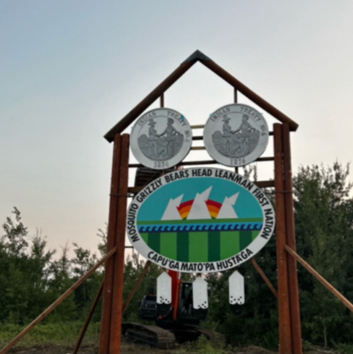 Mosquito Grizzly Bears Head Leanman First Nation entrance sign with twin Treaty 6 medallions, teepees and rainbow motif under a peaked timber frame