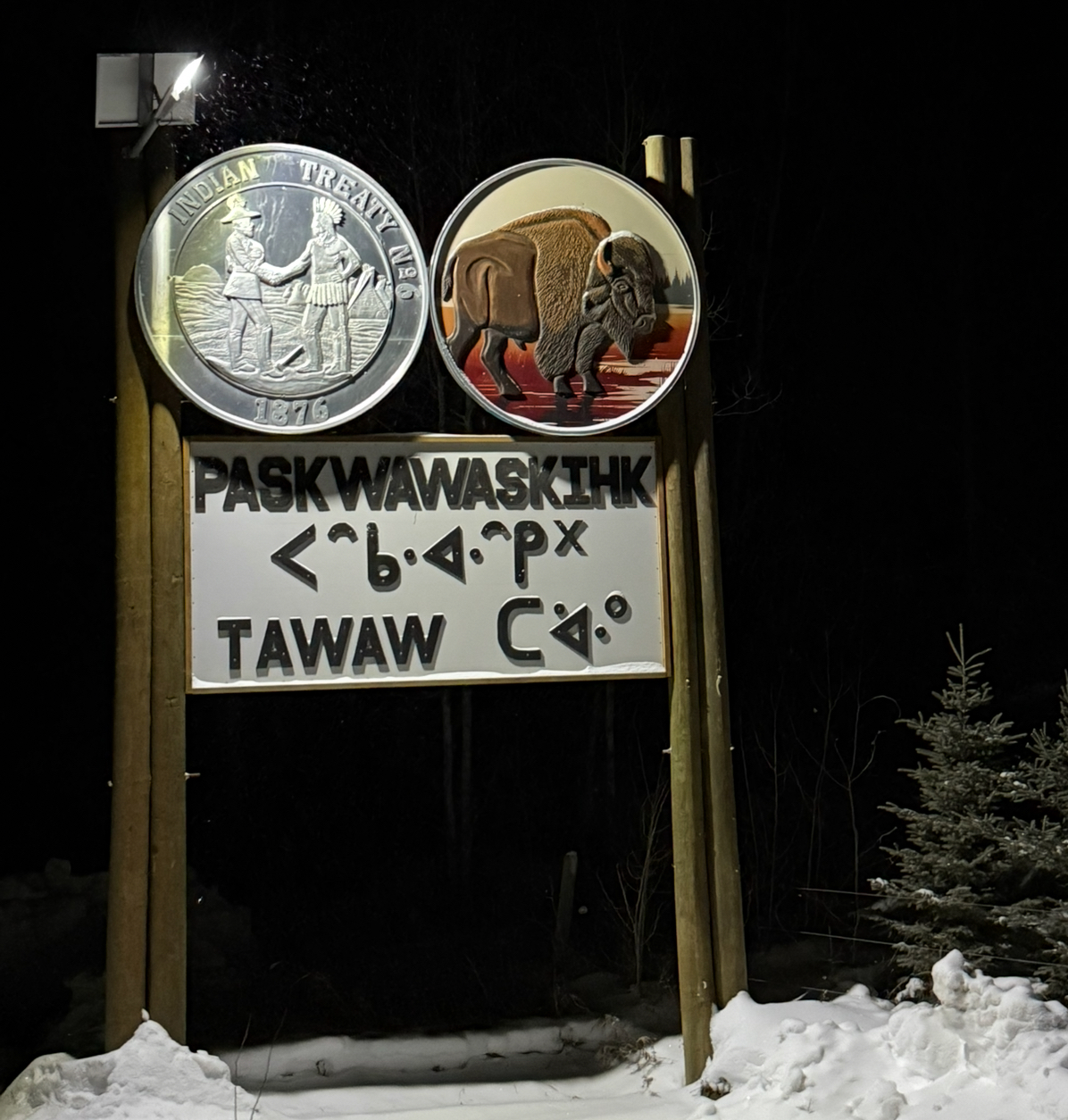 Paskwawaskihk community entrance sign with Treaty 6 medallion and bison, illuminated at night