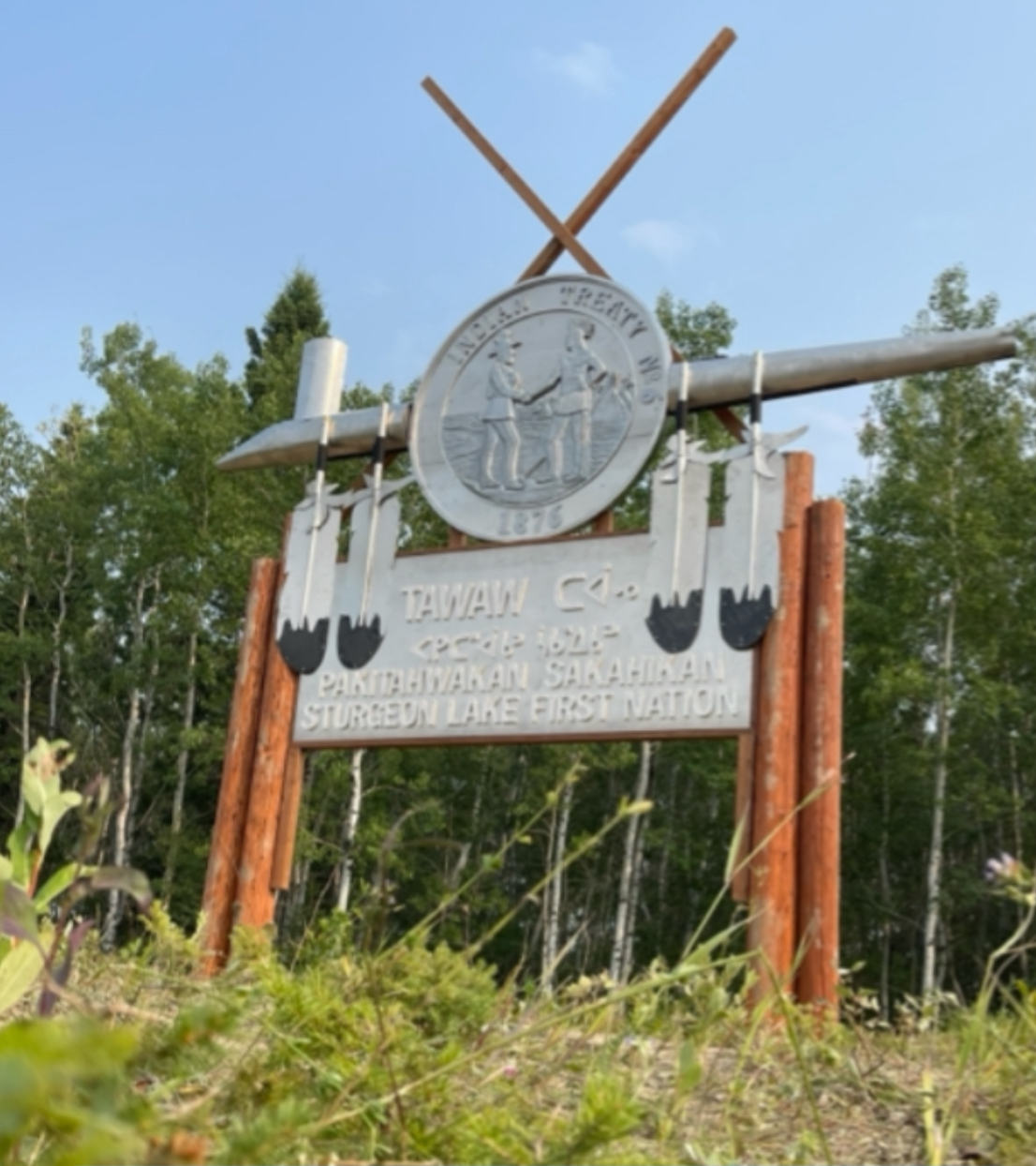 Sturgeon Lake First Nation Tawaw entrance sign with Treaty 6 medallion, crossed pipes and Pakitahwakan Sakahikan syllabics